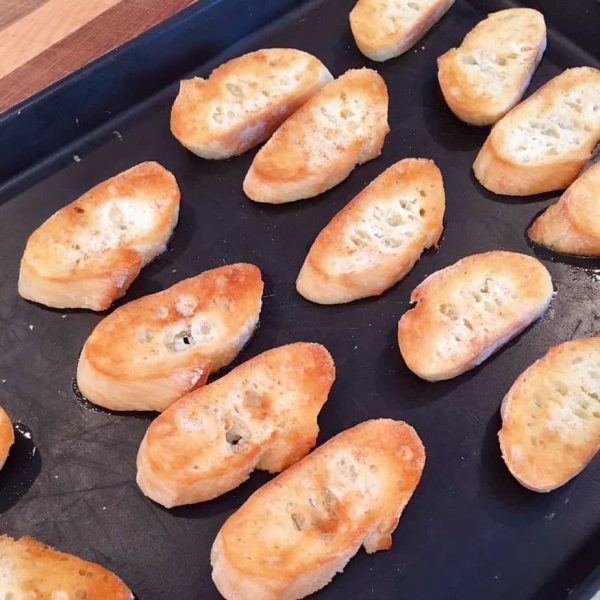 Toasted baguette slices on baking sheet.