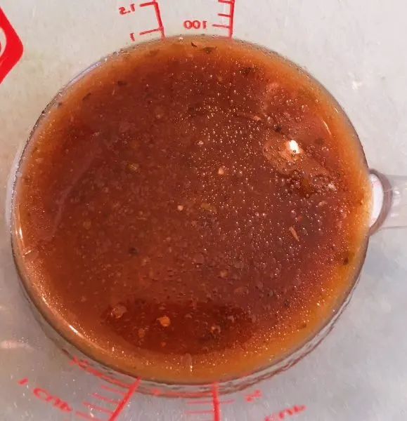 Balsamic dressing in a measuring cup to make dressing.