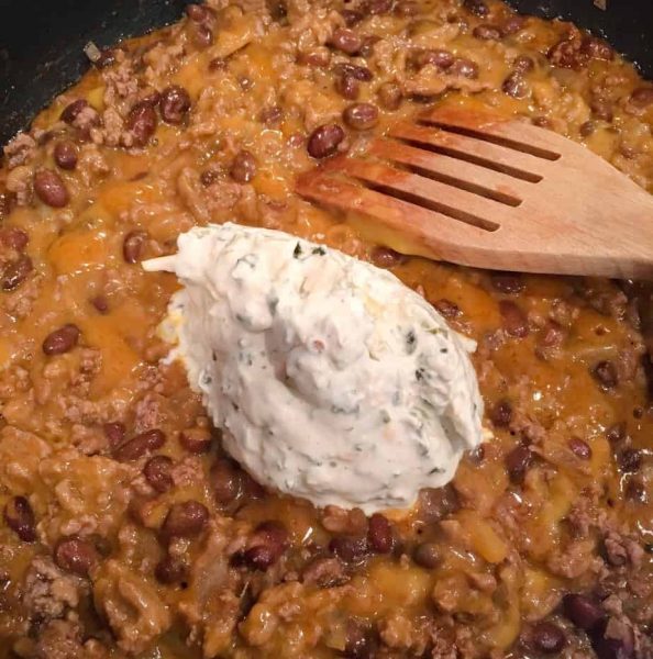 Adding cream cheese dip to hamburger mixture.