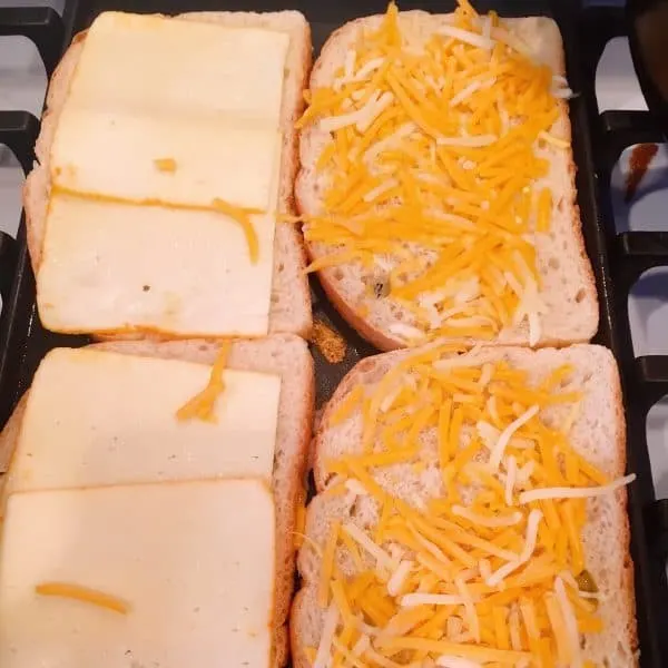 Sourdough bread on a hot grill with slices of cheese.