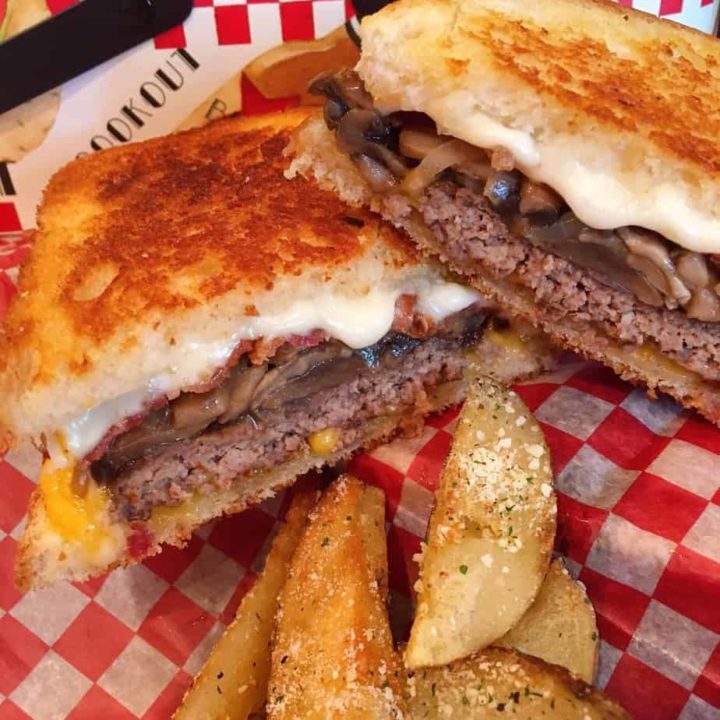 Ultimate Patty Melts on checkered paper with wedge fries