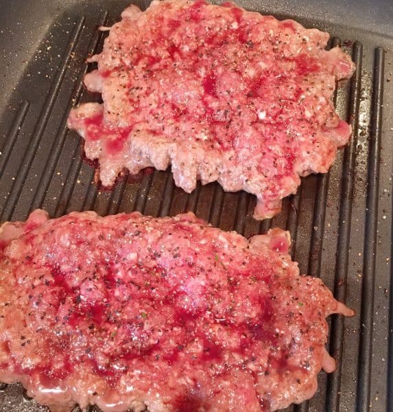Hamburger patties for Patty Melts grilling on the stove top.
