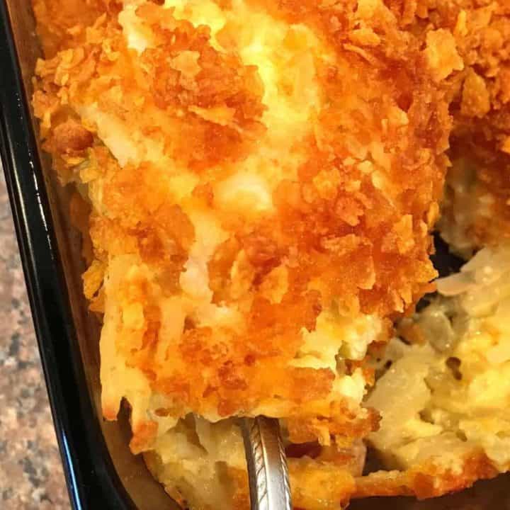 Cheesy Party Potato Casserole with a big scoop being served.