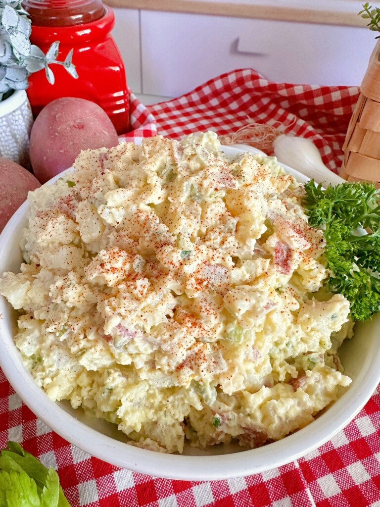 Classic Red Potato Salad in a white serving bowl sprinkled with paprika and garnished with parsley.