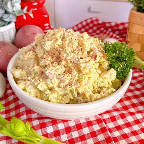 Classic Red Potato Salad in a serving dish on a red and white checkered cloth.