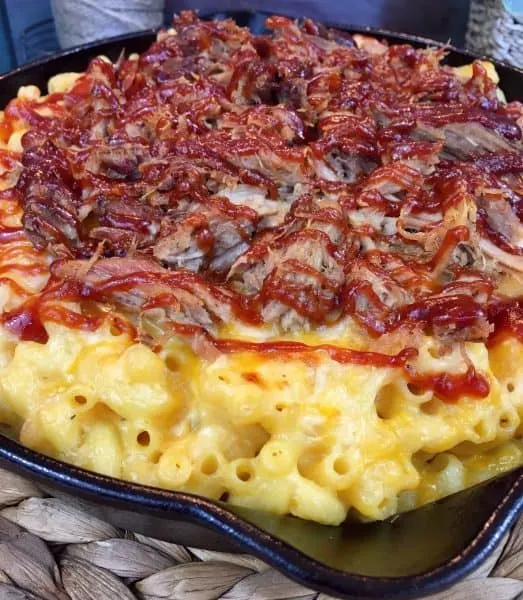 Drizzle BBQ sauce over macaroni and cheese with pulled pork