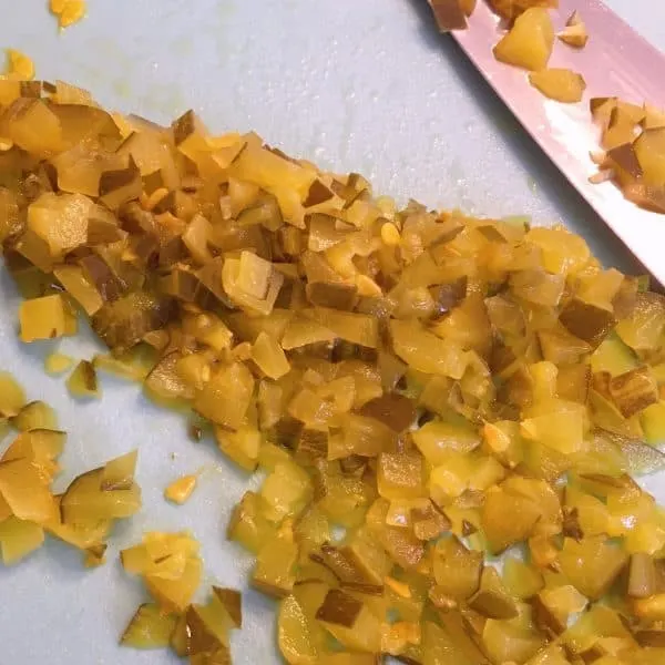 Diced Dill pickles on the cutting board with the knife