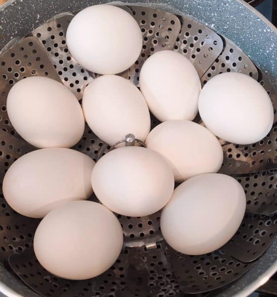 Eggs in a sauce pan with a steamer with eggs.