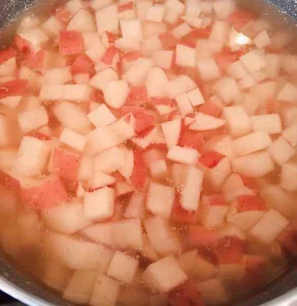 Diced red potatoes covered with water in a large pot on the stove top.