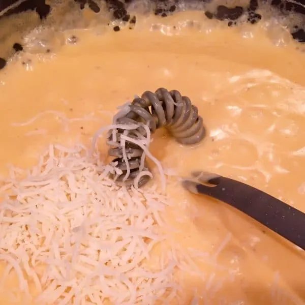 Adding Mozzarella Cheese to cheese sauce in skillet.