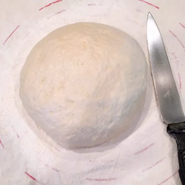 Risen dough ready to cut in half to create two loaves of bread.