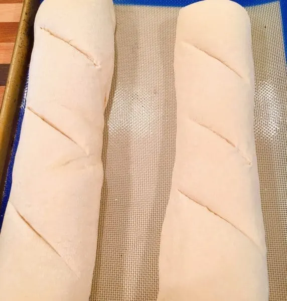 Cutting long slits into each loaf of bread.