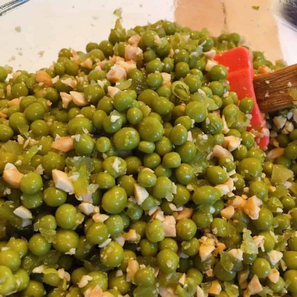 Gently mixing the peas, peanuts, and pickles