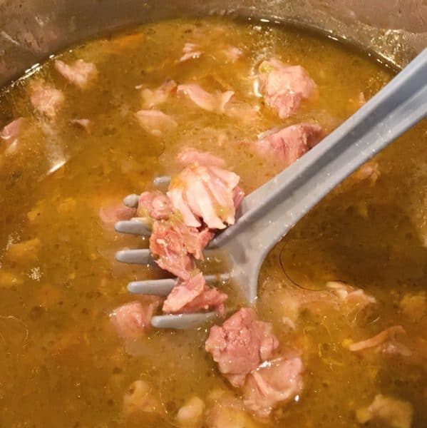Instant Pot Easy Pork Chili Verde in the instant pot being broken up with a potato masher