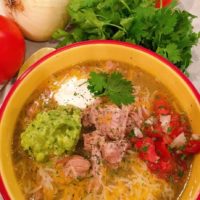 Instant Pot Chili Verde in a bowl with pico, guacamole, sour cream, and cheese