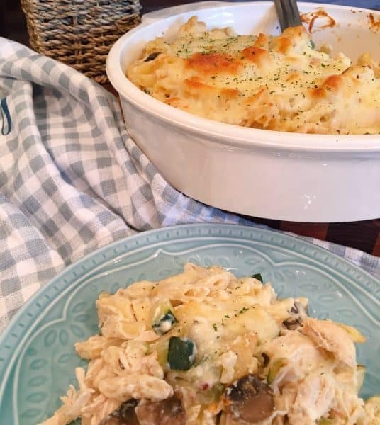 Serving of Chicken Zucchini Pasta Casserole with Casserole in the background