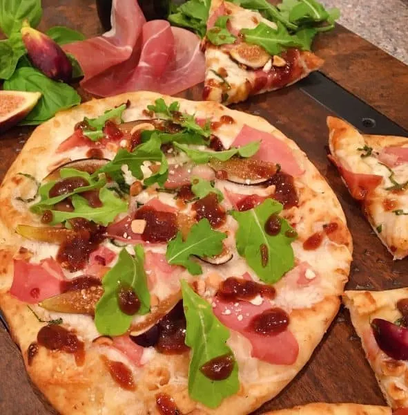 Fig Prosciutto Hazelnut Pizza on a board with props