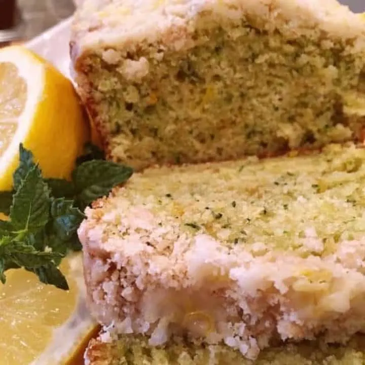 Lemon Zucchini Bread with Crumb topping sliced and on serving tray with lemon slices.