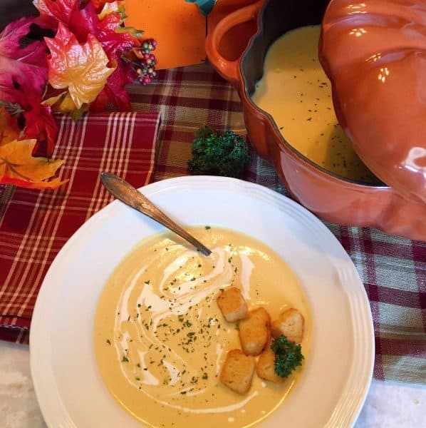 Soup in bowl and big pumpkin cast iron pot.