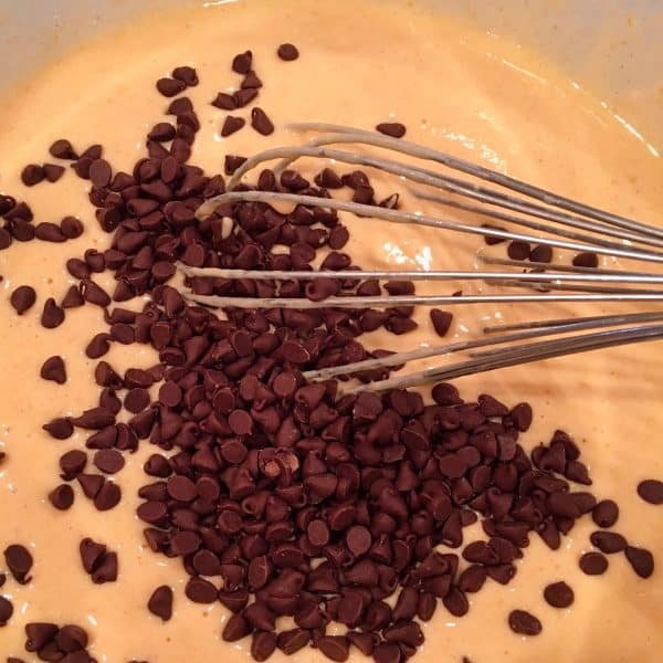 Adding mini chocolate chips to pancake batter.