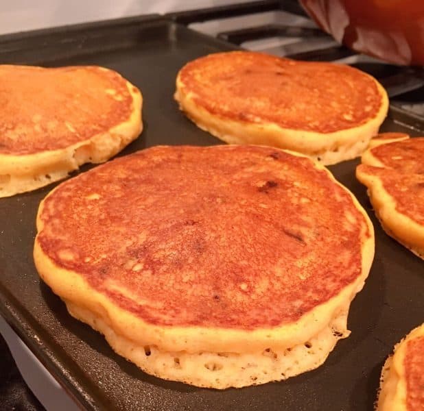 Side view of raised pancakes on the griddle.