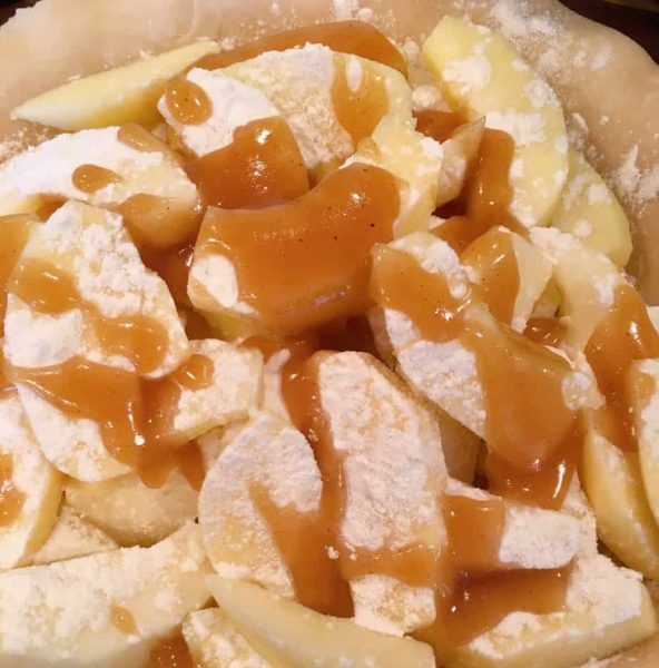 half the caramel sauce poured over the half the apples in the pie crust.