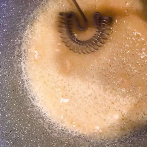 Adding flour to melted butter to create a paste base for the caramel sauce.