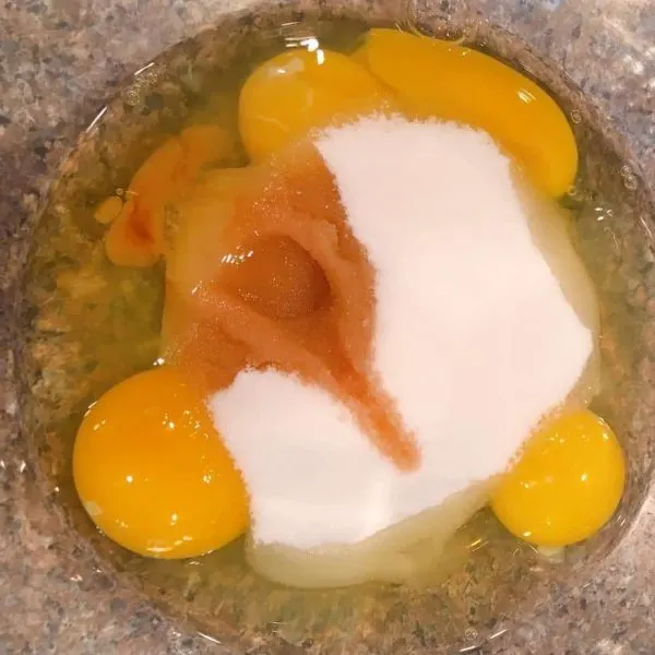 Bowl with eggs, sugar, milk and vanilla.