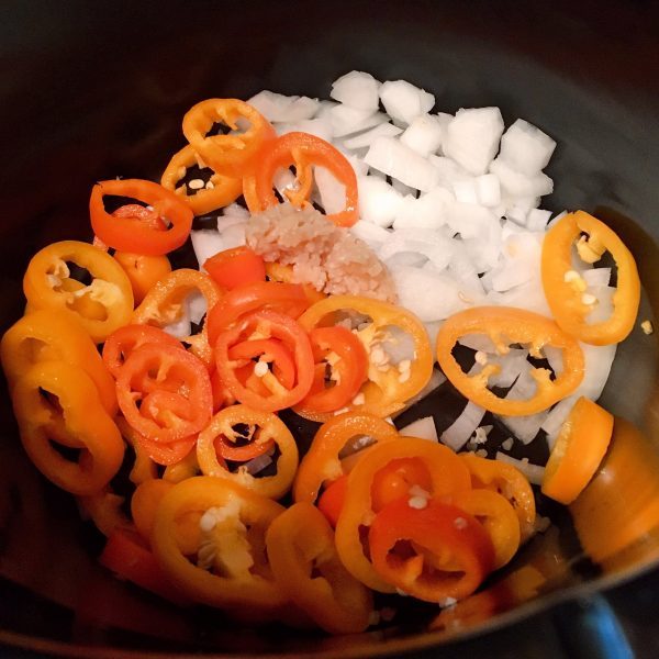 Italian Sweet peppers and onions in the bottom of a slow cooker
