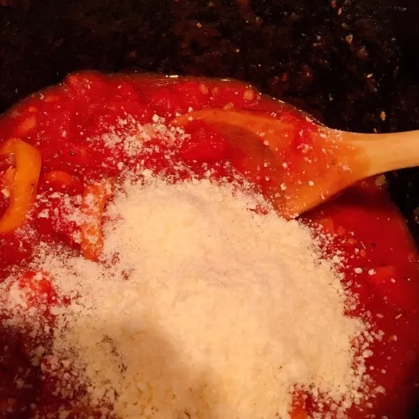 Adding grated Parmesan cheese to tomato sauce