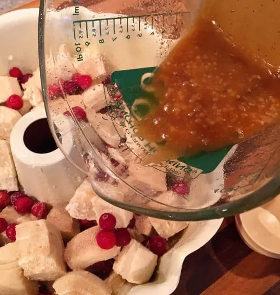 pouring brown sugar butter mixture over cranberry orange rolls.