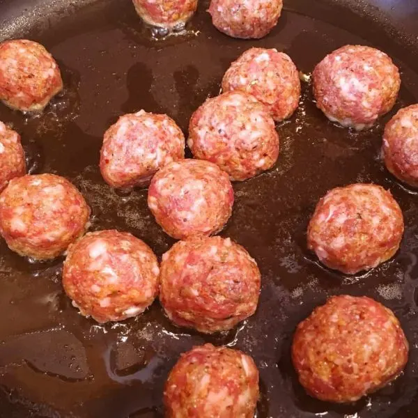 Sausage balls cooking in oil in a skillet
