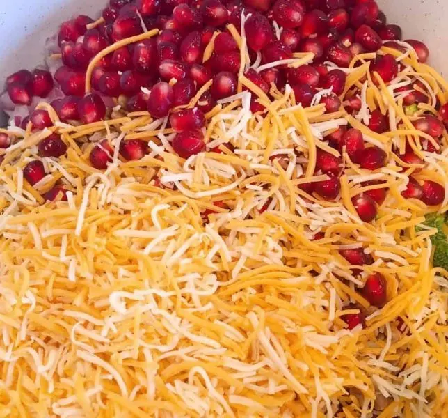 Adding Cheese, sunflower seeds, and pomegranate seeds to salad