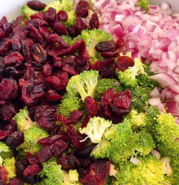 Adding onion, and dried cranberries to broccoli