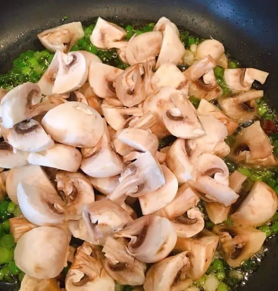 cooking mushroom and green onions over medium heat