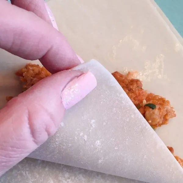 folding sides of egg roll wrapper in over filling