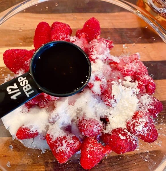 Raspberries, sugar, and amaretto in a small bowl