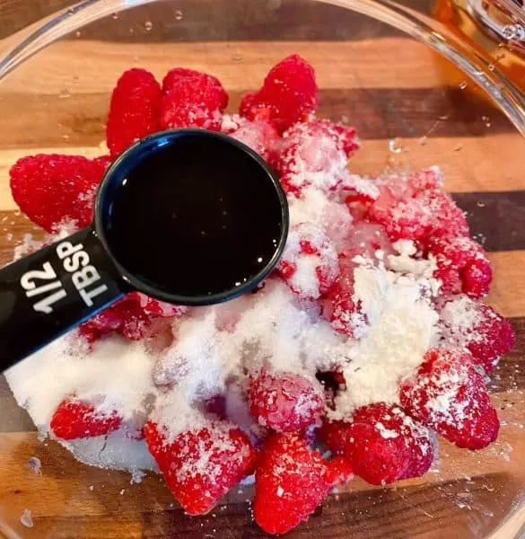 Raspberries, sugar, and amaretto in a small bowl