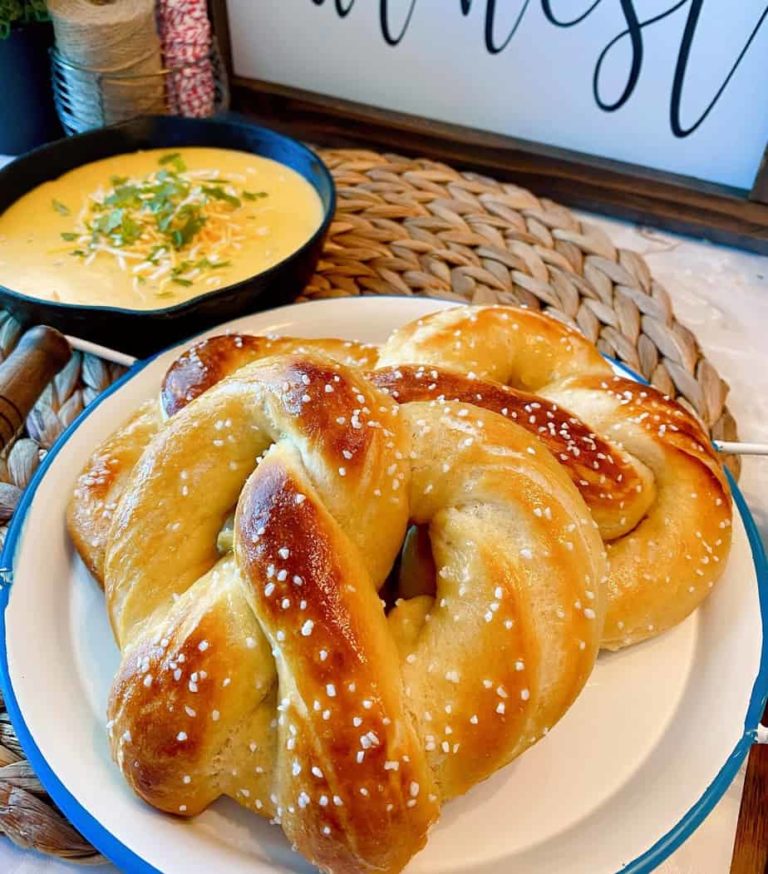Easy Soft Homemade Pretzels on a plate with cheese dipping sauce in the background.