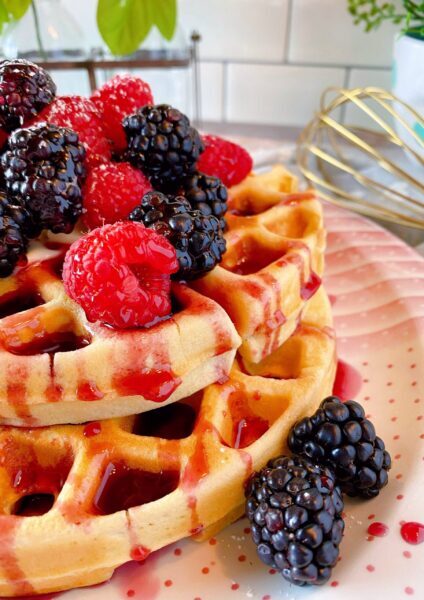 stack of waffles with syrup and fresh berries