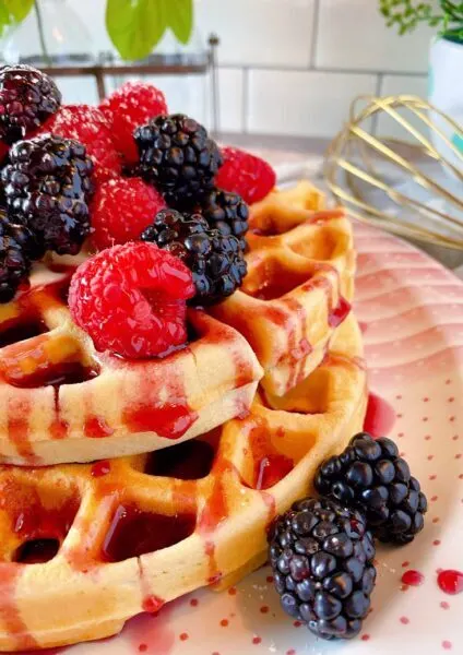 stack of waffles with syrup and fresh berries