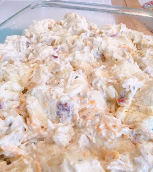 chicken and cheese spread out in casserole dish ready for baking