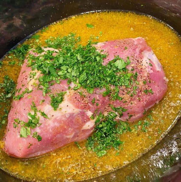 adding chopped cilantro to pork roast