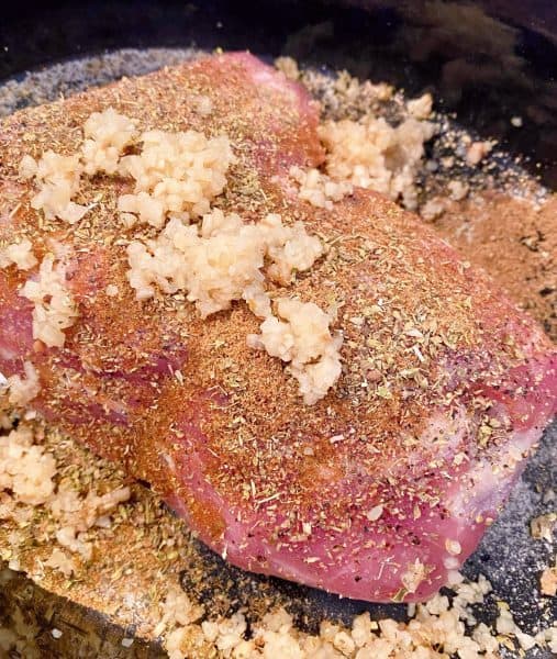 Pork Roast in bottom of slow cooker with spices and garlic