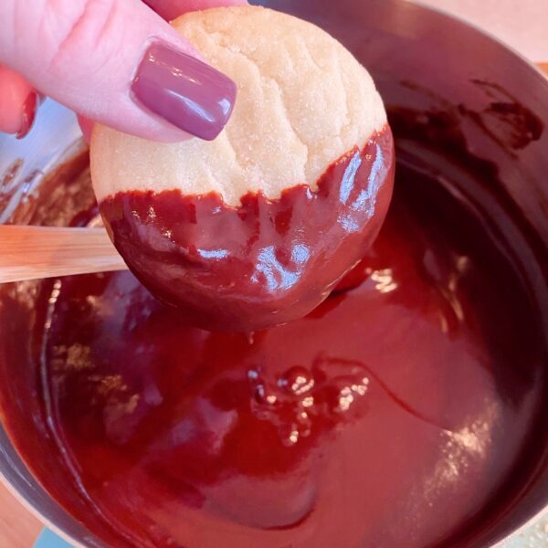 dunking sugar cookies into melted chocolate glaze