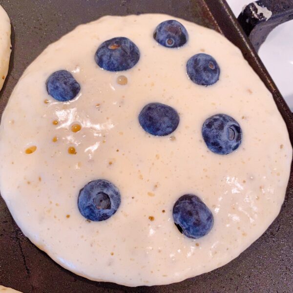 Adding blueberries to each baking pancake