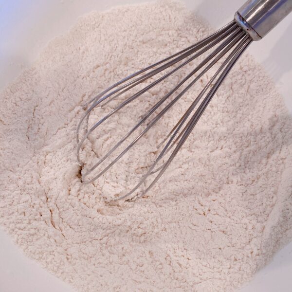 Flour, sugar and other dry ingredients in a bowl for blueberry pancakes