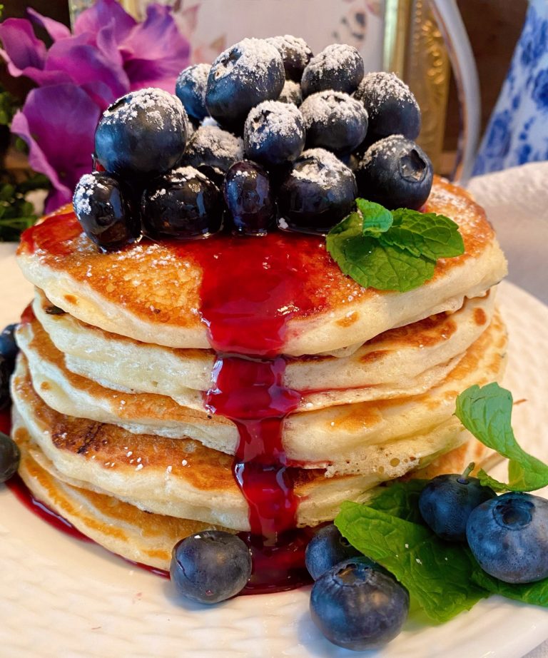 Homemade Blueberry Buttermilk Pancakes stacked high with fresh blueberries and syrup.