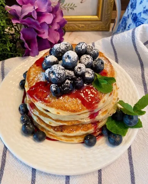 Blueberry Buttermilk Pancakes in a stack with syrup and fresh blueberries
