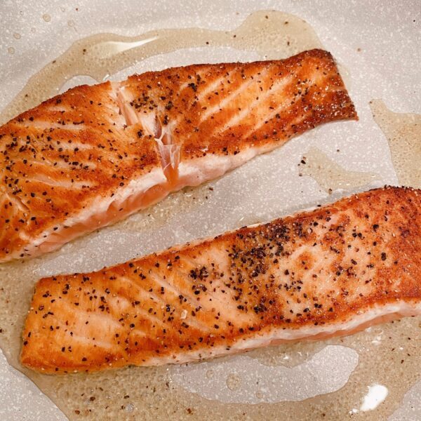 Salmon searing in the skillet on top of the stove